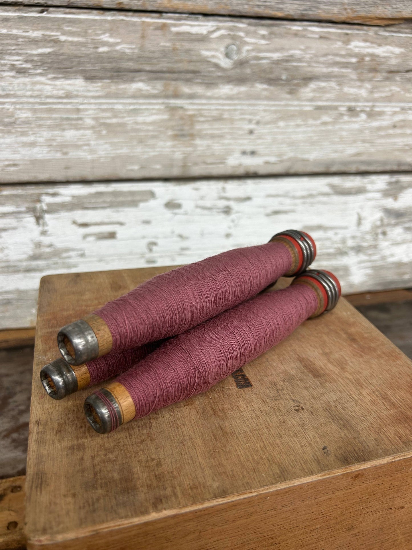 Dusty Rose Yarn Quill, 6.5-inch fiber art supply wrapped in soft yarn. Perfect for crafting and home decor, set on a rustic wooden surface.